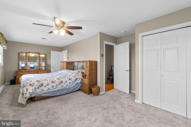 bedroom featuring a ceiling fan, a closet, light carpet, and baseboards