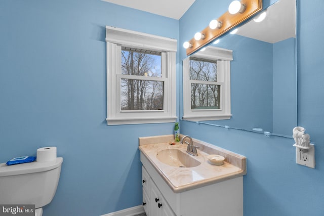 bathroom featuring baseboards, vanity, and toilet