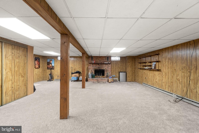 finished below grade area with carpet floors, a fireplace, a baseboard radiator, and wooden walls