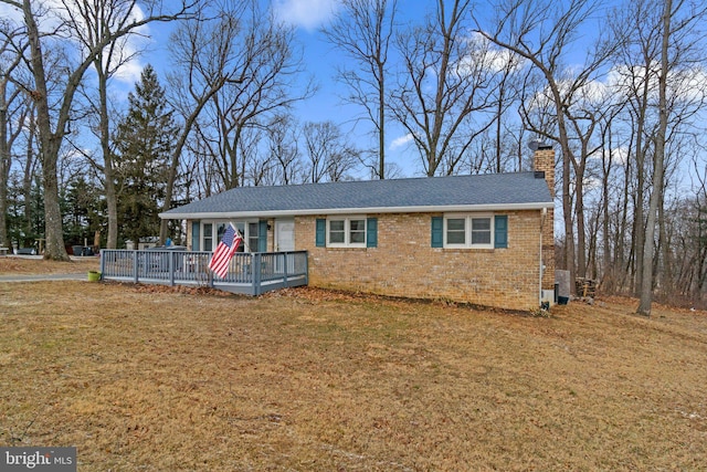 ranch-style house with a front yard, brick siding, a chimney, and a wooden deck