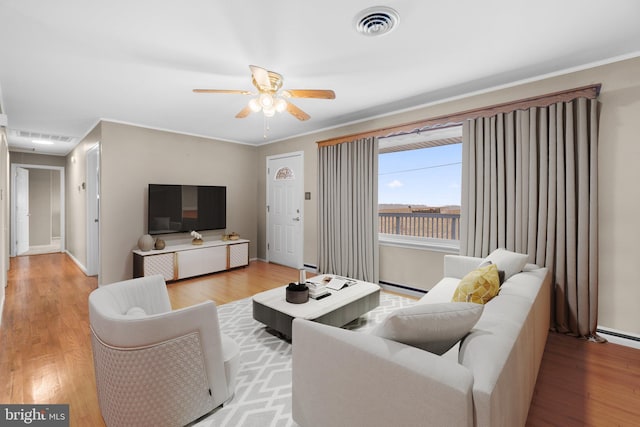 living room featuring light wood-style floors, visible vents, and crown molding