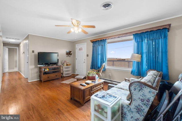 living area featuring a ceiling fan, visible vents, wood finished floors, and a baseboard heating unit