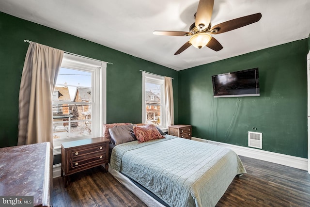 bedroom with a ceiling fan, dark wood finished floors, visible vents, and baseboards