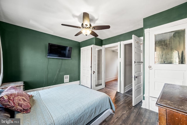 bedroom with dark wood-style floors, visible vents, ceiling fan, and baseboards