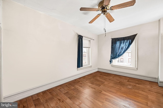 spare room with a ceiling fan, light wood-style flooring, and baseboards