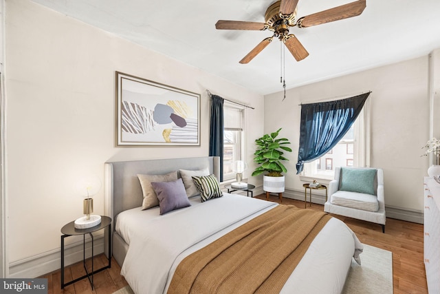 bedroom with a ceiling fan, baseboards, and wood finished floors