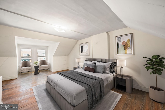 bedroom with lofted ceiling, baseboards, and wood finished floors