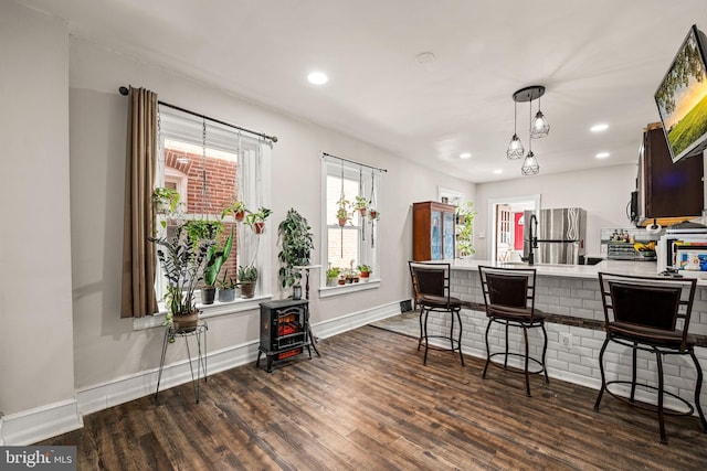 kitchen with dark wood finished floors, recessed lighting, light countertops, a wood stove, and baseboards