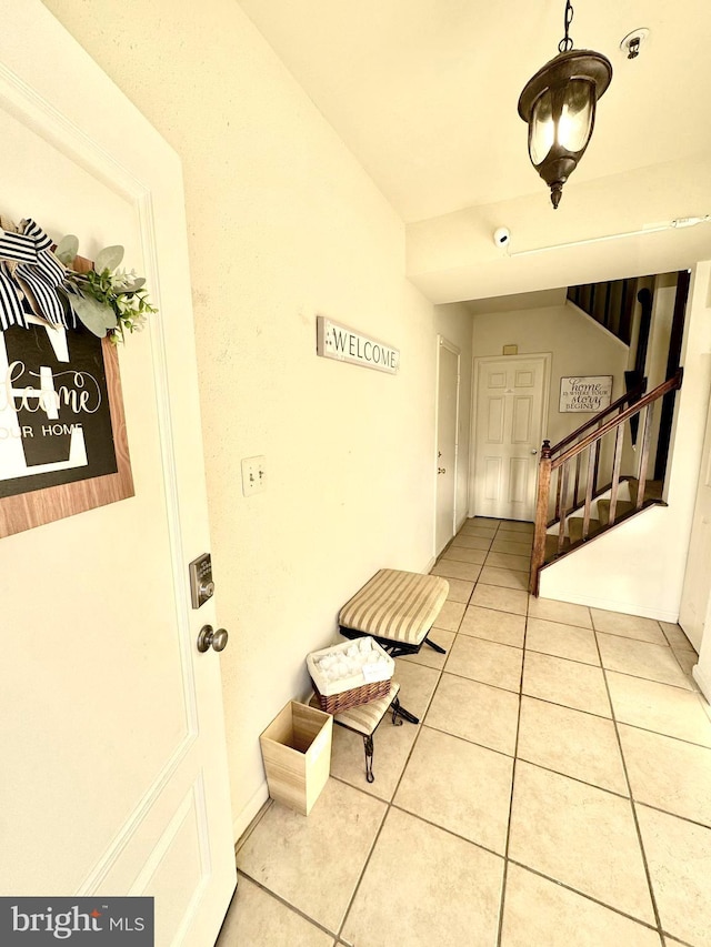 interior space with light tile patterned floors, stairs, and vaulted ceiling