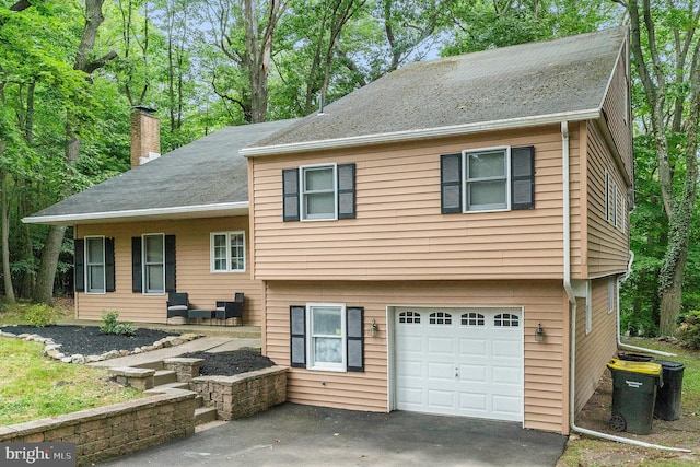 split level home with a garage, driveway, and a chimney