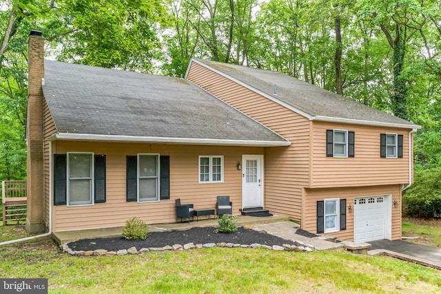 split level home with driveway, a shingled roof, entry steps, a chimney, and a garage