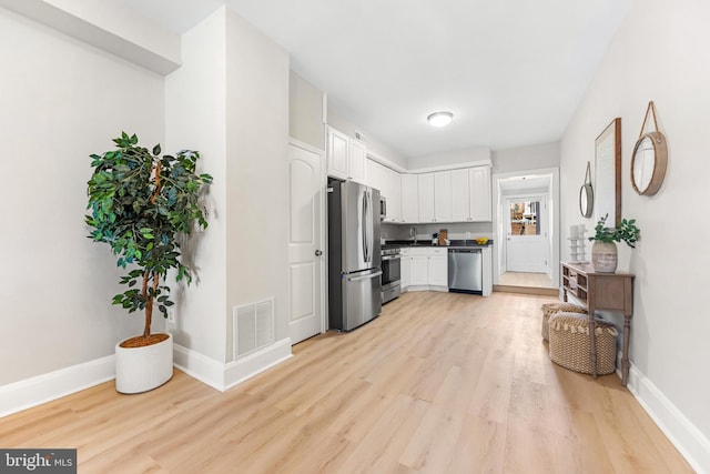 kitchen featuring white cabinetry, stainless steel appliances, and light wood-type flooring