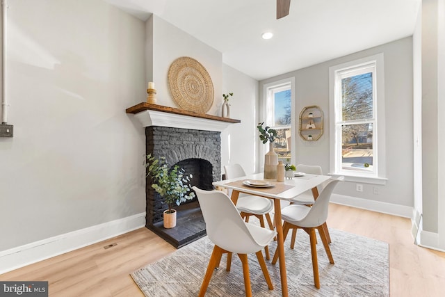 dining space featuring a stone fireplace and light wood-type flooring