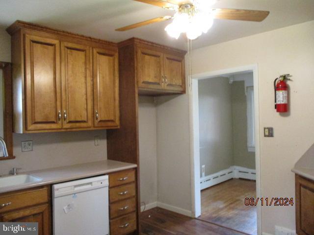 kitchen with sink, baseboard heating, dark hardwood / wood-style floors, dishwasher, and ceiling fan