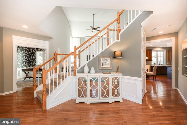 stairs with recessed lighting, a wainscoted wall, a decorative wall, wood finished floors, and a ceiling fan