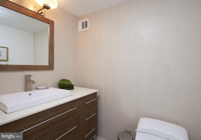 bathroom featuring tile walls, vanity, and toilet