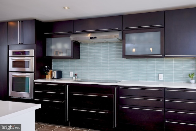 kitchen featuring black electric stovetop, exhaust hood, stainless steel double oven, dark brown cabinets, and tasteful backsplash