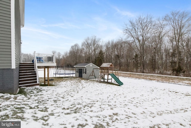 snow covered playground featuring a trampoline and a shed