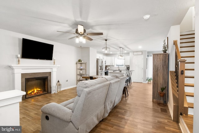 living room with ceiling fan, sink, and light hardwood / wood-style floors