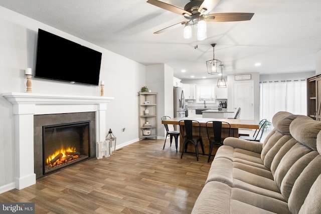 living room with ceiling fan, sink, and light hardwood / wood-style floors