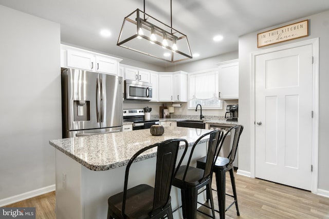 kitchen with pendant lighting, appliances with stainless steel finishes, a center island, and white cabinets