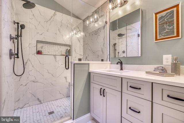 bathroom featuring lofted ceiling, a marble finish shower, and vanity