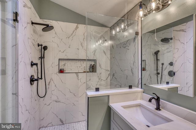 bathroom with vaulted ceiling, a marble finish shower, and vanity