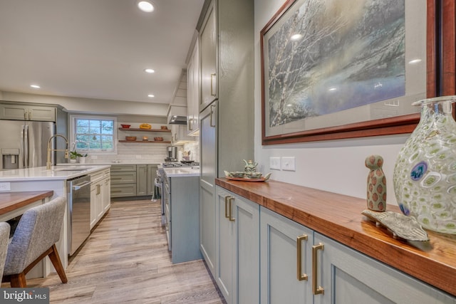 kitchen with butcher block countertops, appliances with stainless steel finishes, a sink, and gray cabinetry