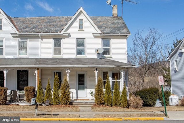 townhome / multi-family property with a chimney, a high end roof, and covered porch