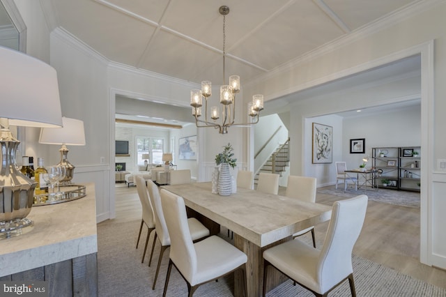 dining space featuring stairs, ornamental molding, light wood-type flooring, and a notable chandelier