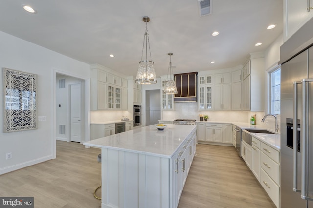 kitchen with glass insert cabinets, a sink, a kitchen island, white cabinetry, and decorative light fixtures