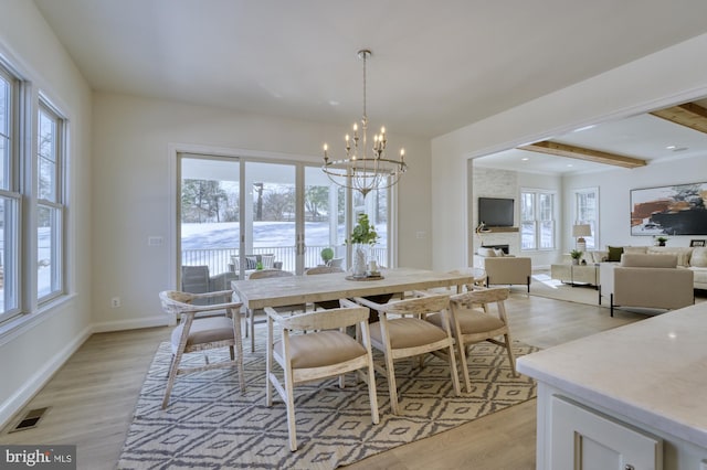 dining space featuring light wood finished floors, baseboards, visible vents, an inviting chandelier, and beam ceiling