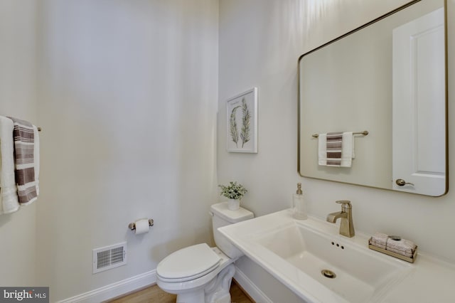 bathroom featuring toilet, visible vents, and a sink