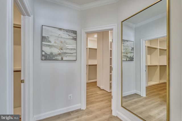 corridor with ornamental molding, light wood-type flooring, and baseboards