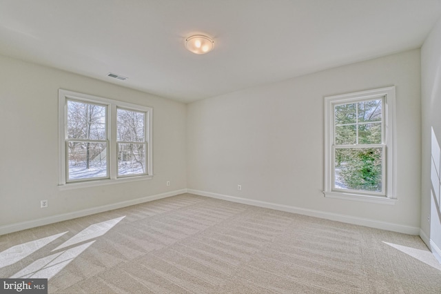 empty room with light colored carpet, visible vents, and baseboards