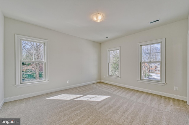 unfurnished room featuring light colored carpet, visible vents, and baseboards