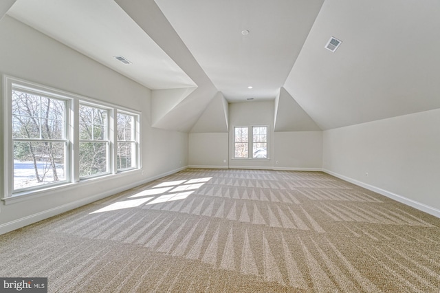 additional living space featuring baseboards, visible vents, and light colored carpet