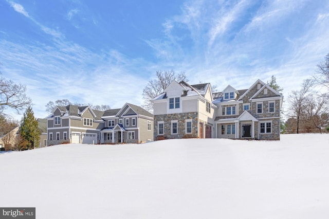 shingle-style home featuring a garage, a residential view, and stone siding