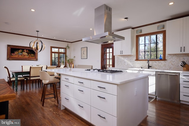 kitchen featuring island range hood, gas stovetop, light countertops, stainless steel dishwasher, and decorative light fixtures