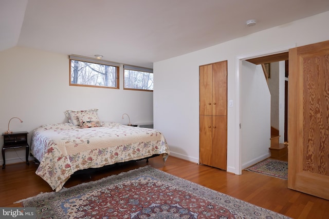 bedroom with vaulted ceiling, baseboards, and wood finished floors