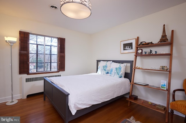 bedroom with dark wood-style floors, radiator heating unit, visible vents, and baseboards