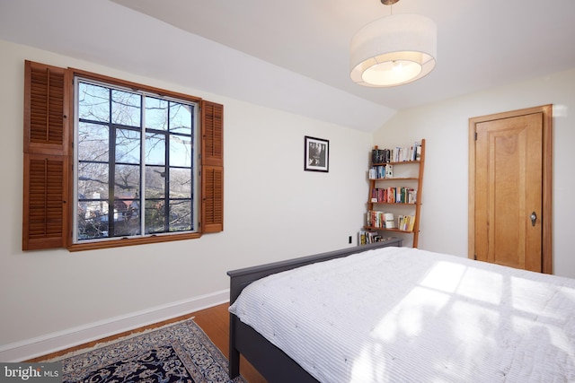 bedroom with lofted ceiling, baseboards, and wood finished floors