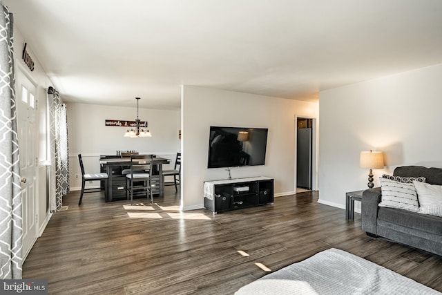 living area with dark wood-style floors, an inviting chandelier, and baseboards