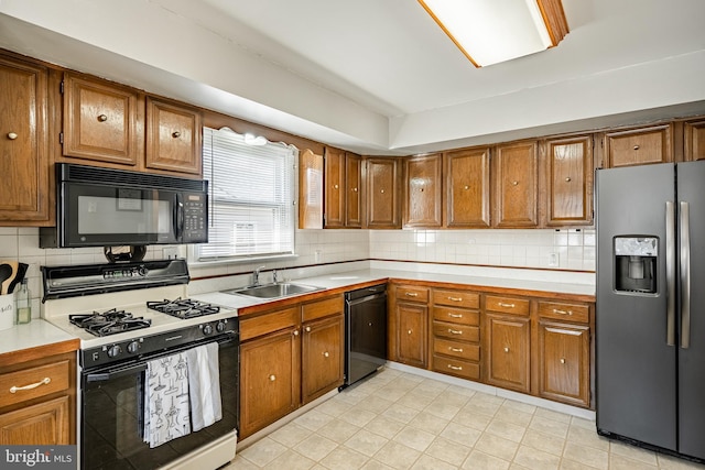 kitchen featuring brown cabinets, light countertops, a sink, and black appliances