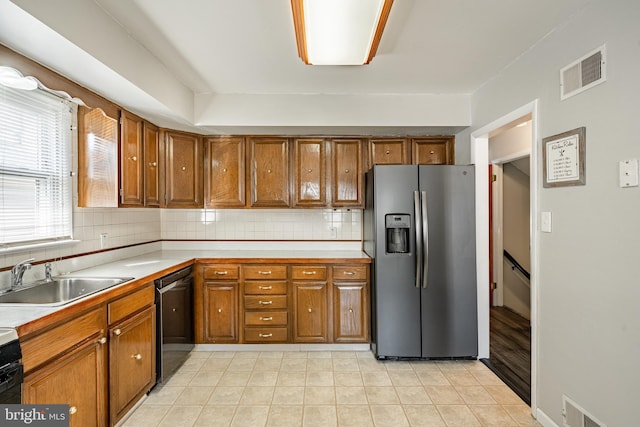 kitchen featuring brown cabinets, light countertops, visible vents, dishwasher, and stainless steel fridge with ice dispenser