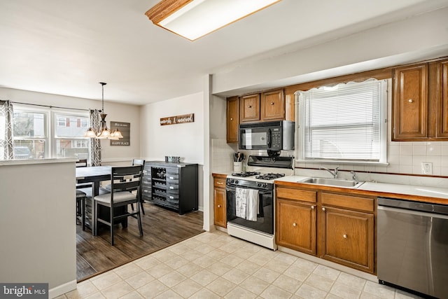 kitchen with black microwave, light countertops, stainless steel dishwasher, hanging light fixtures, and gas range