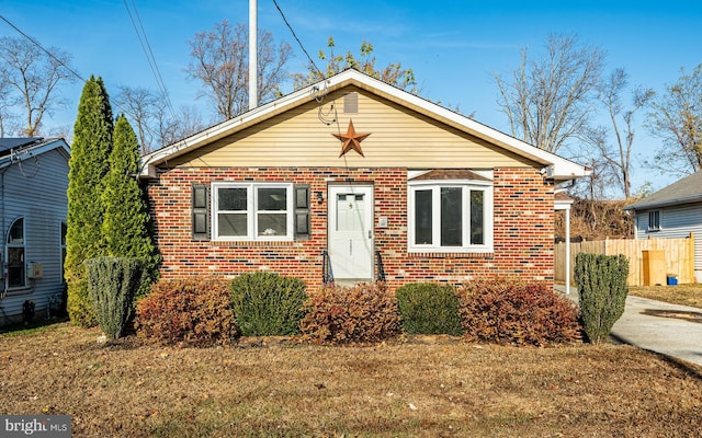 bungalow-style home featuring a front yard, brick siding, and fence