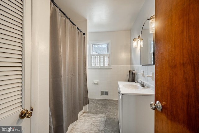 bathroom with tile walls, visible vents, a closet, and vanity