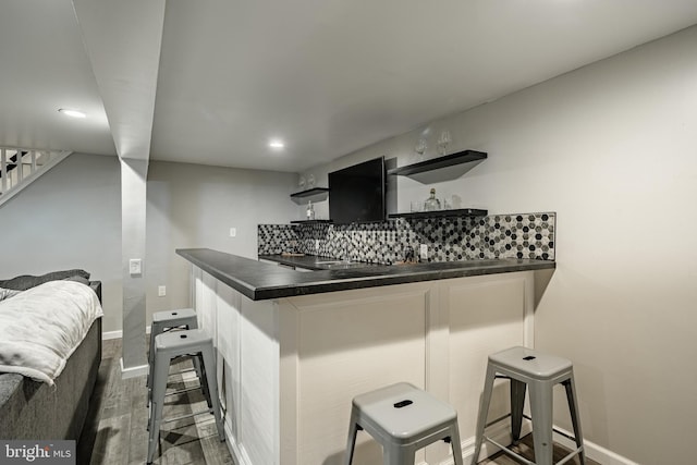 kitchen featuring a peninsula, a kitchen breakfast bar, dark cabinetry, open shelves, and dark countertops