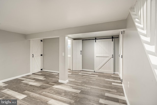 finished below grade area with light wood-style floors, baseboards, and a barn door